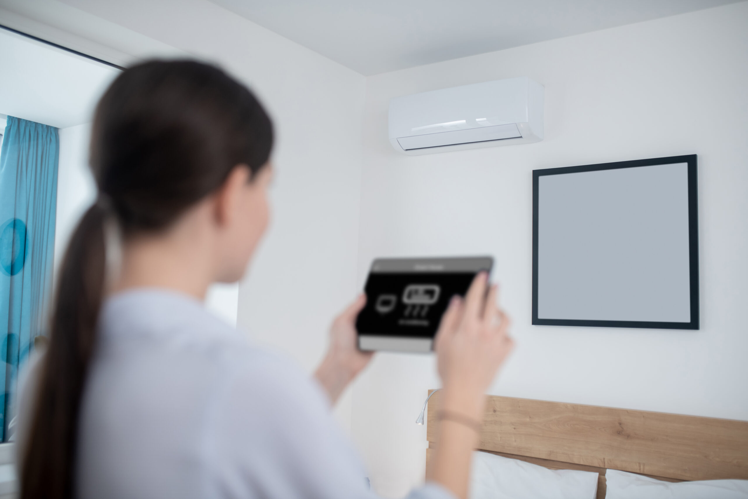Woman turning on an air conditioner using a tablet